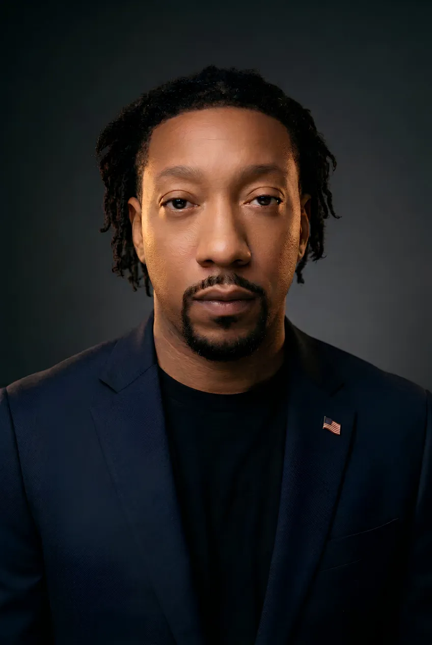 Studio portrait of The Navigator in a navy blazer with a small U.S. flag pin — a Navy veteran and neuroscience practitioner.