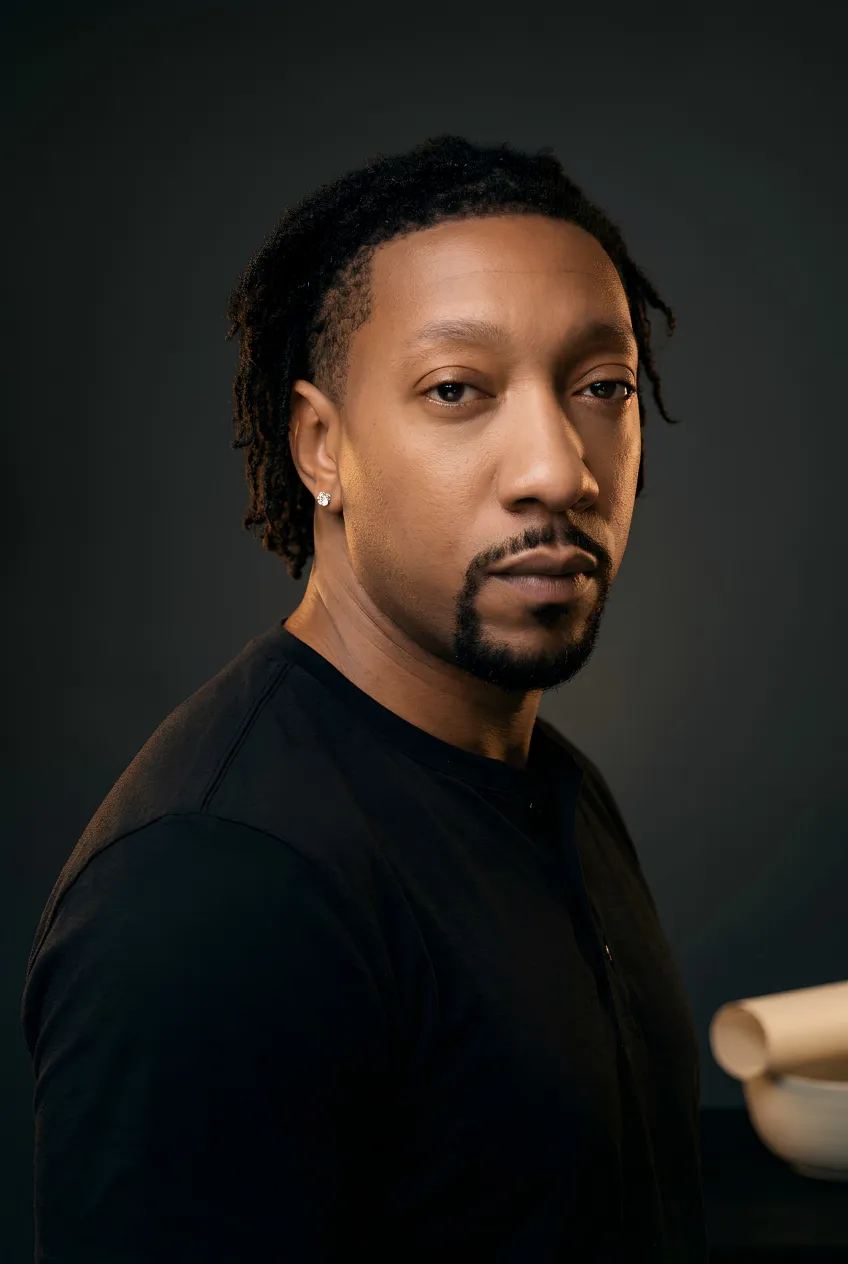 Side-lit studio portrait of The Navigator in a black henley against a dark backdrop.